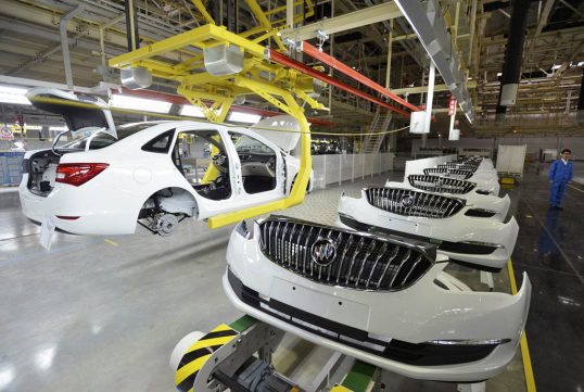 An employee looks on next to an assembly production line of Buick cars at a General Motors factory in Wuhan