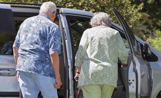 Overweight Senior Couple Getting Into Minivan Car